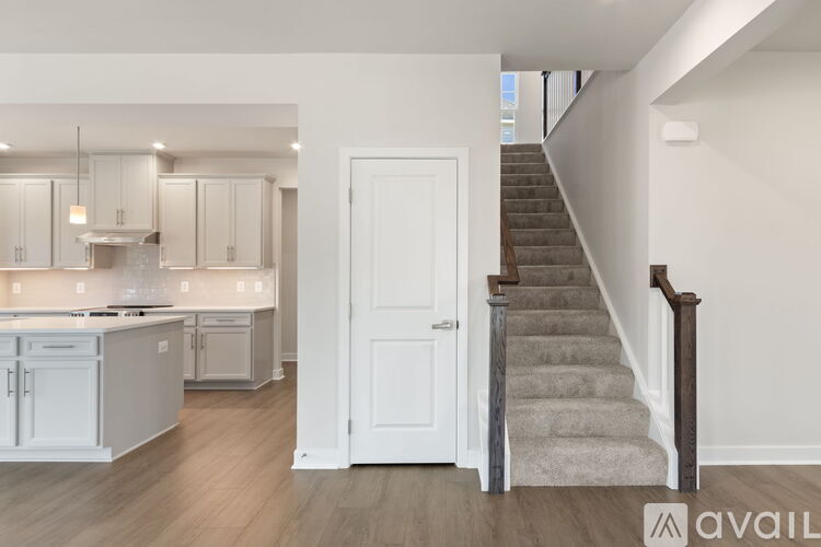 A modern kitchen with white cabinets and a staircase leading to the upper floor.