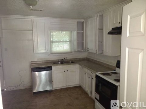 A kitchen with white cabinets and a stainless steel trash can.