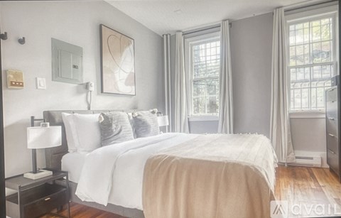A bedroom with a large bed and a window with curtains.