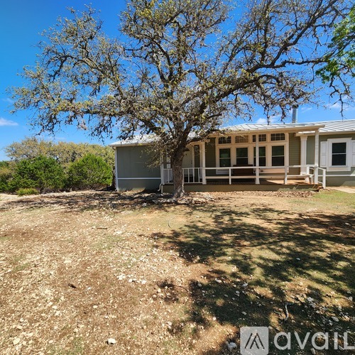 A house with a porch and a tree in front of it.