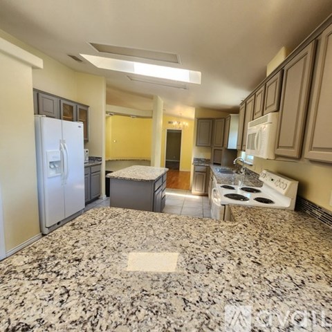 A kitchen with granite countertops and a white refrigerator.