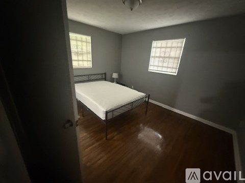 A bedroom with a bed, a window with blinds, and a door.