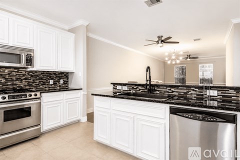 A kitchen with white cabinets and black countertops.