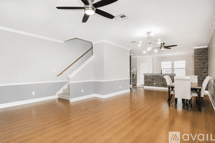 A spacious room with a dining table and chairs, a staircase, and a ceiling fan.