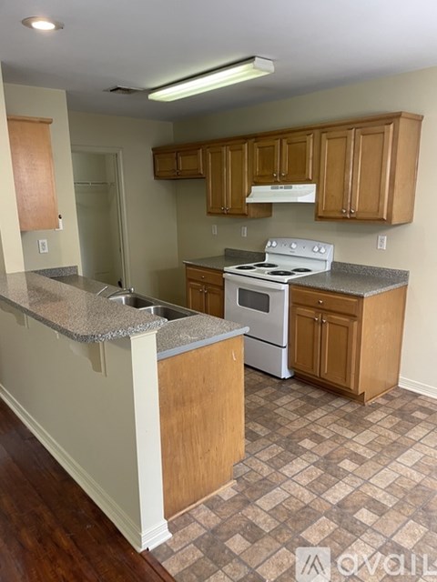 A kitchen with wooden cabinets and a white stove top oven.