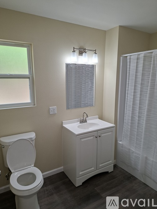 A bathroom with a toilet, sink, and window.