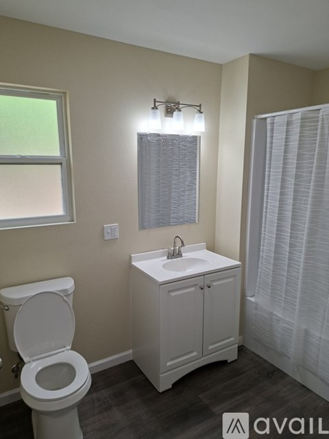 A bathroom with a toilet, sink, and window.