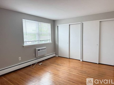 A room with a window, a fan, and a wooden floor.