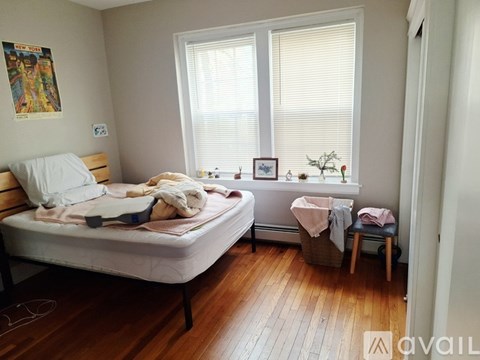 A bedroom with a bed, a chair, and a window.