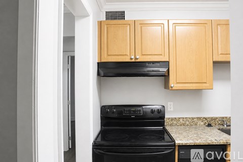 A kitchen with a black stove and wooden cabinets.