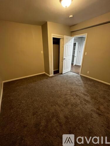 A carpeted room with a doorway leading to another room.