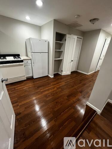 A kitchen with white appliances and wooden floors.