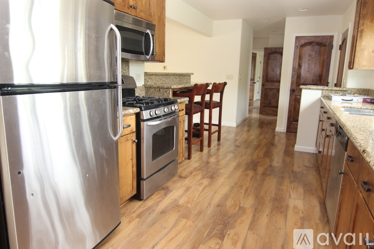 A kitchen with a stainless steel refrigerator, oven, and wooden floors.