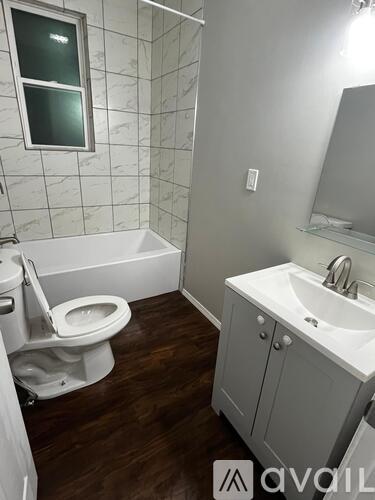 A white toilet is in a small bathroom with a white sink and a mirror.