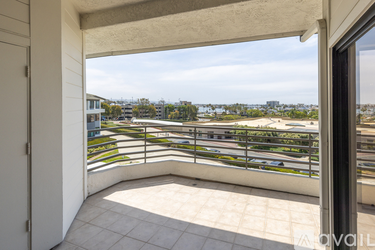 A balcony with a view of a parking lot and buildings.