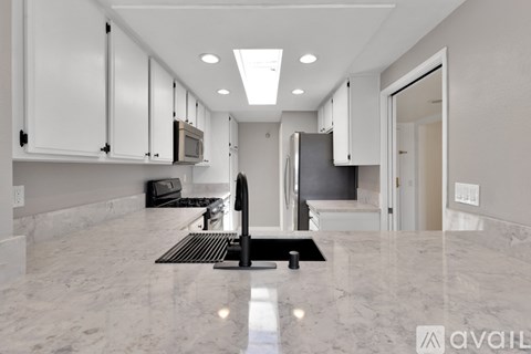 A kitchen with white cabinets and a marble countertop.