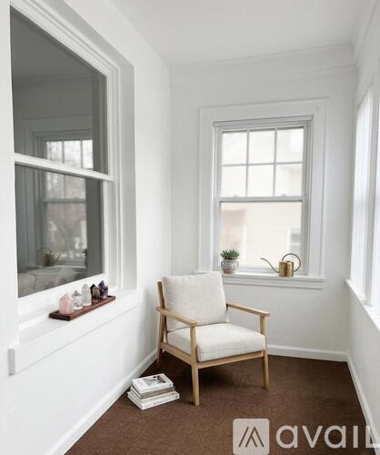 A chair sits in a corner of a room with a window.