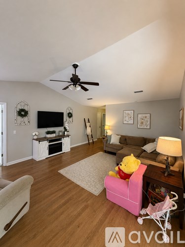 A living room with a pink chair and a ceiling fan.
