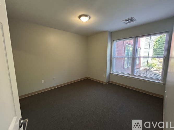 A room with a window overlooking a building and trees.