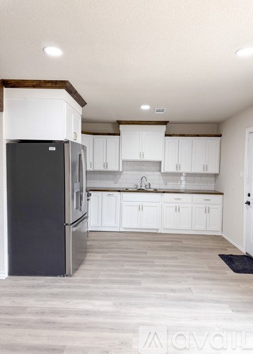 A black refrigerator in a kitchen with white cabinets.