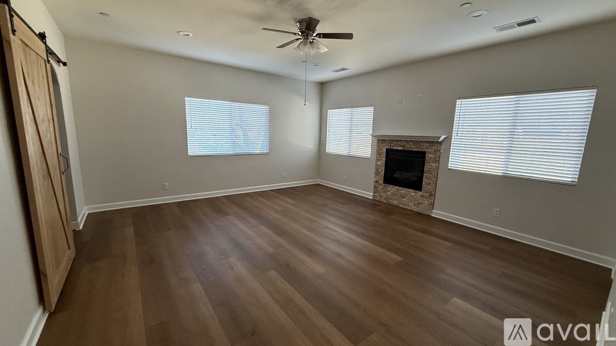 A spacious room with wooden floors and a fireplace.