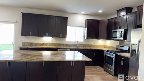 A kitchen with dark brown cabinets and a marble countertop.