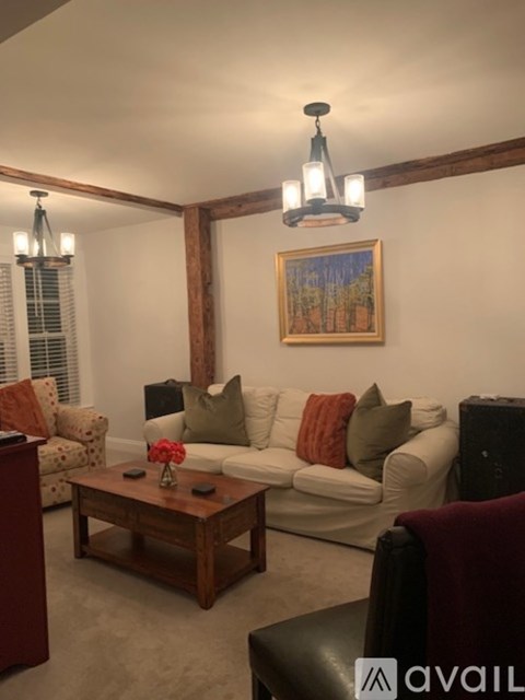A living room with a white couch, a wooden coffee table, and a painting on the wall.