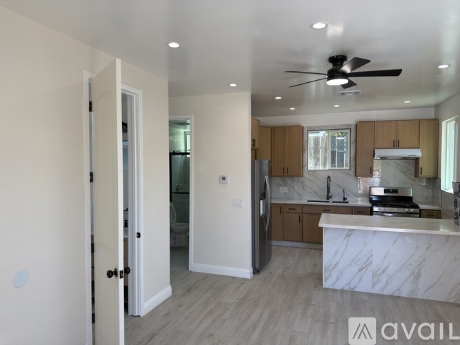 A modern kitchen with a marble countertop and a ceiling fan.