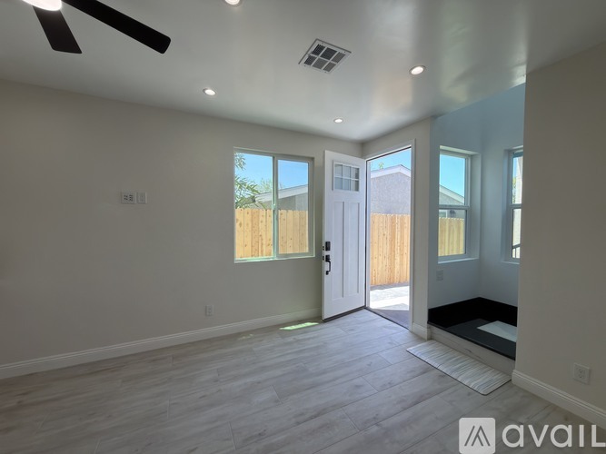 A spacious room with a ceiling fan and sliding glass doors leading to a backyard.
