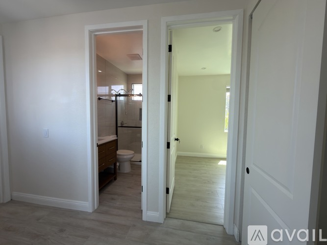 A bathroom with a toilet and a shower is visible through an open door.