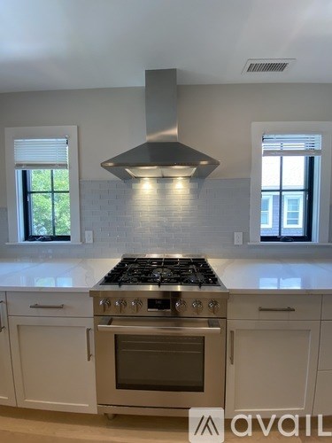 A modern kitchen with a stove top oven and white cabinets.