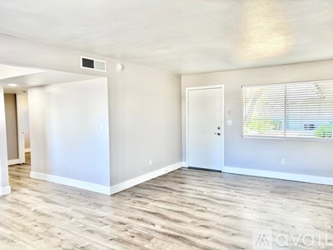 A spacious room with wooden flooring and white walls.