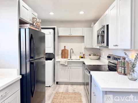 A kitchen with white cabinets and a black refrigerator.