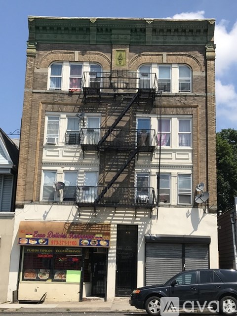 A building with a fire escape and a car parked in front.