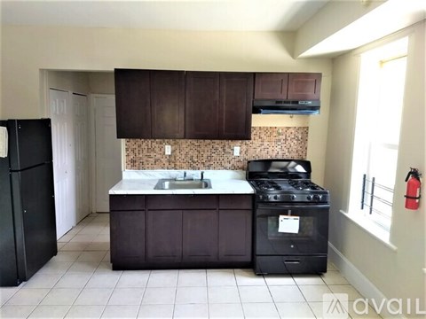 A kitchen with a black stove and brown cabinets.