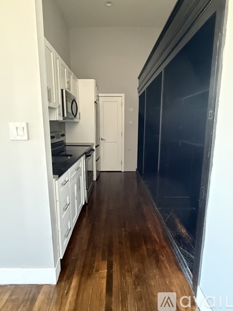 A kitchen with white cabinets and a black fridge.