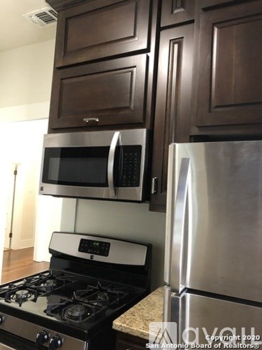 A kitchen with a stove, microwave, and refrigerator.