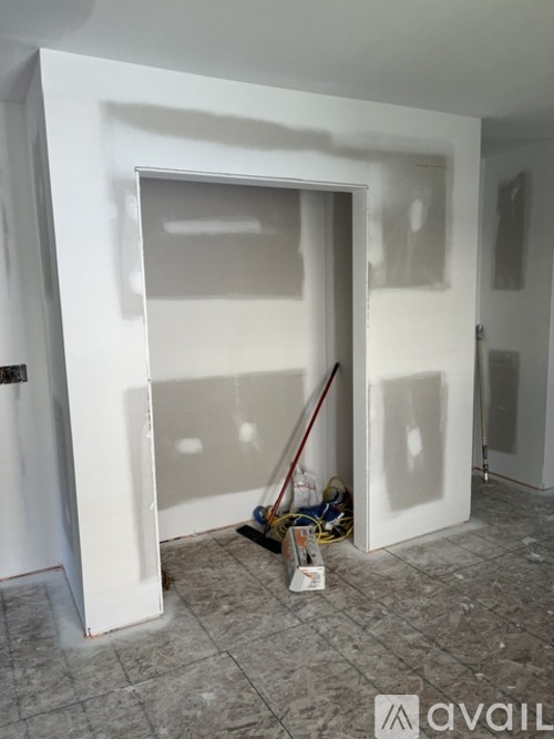 A room with a white door and a red broom.