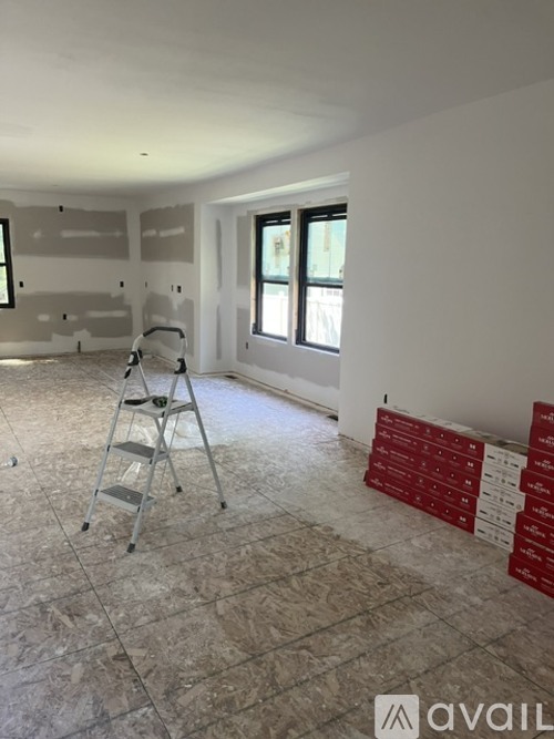 A room with a ladder and some red boxes on the floor.