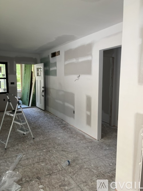 A room with a ladder and a wall with a lot of white space.