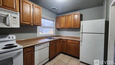 A kitchen with white appliances and wooden cabinets.