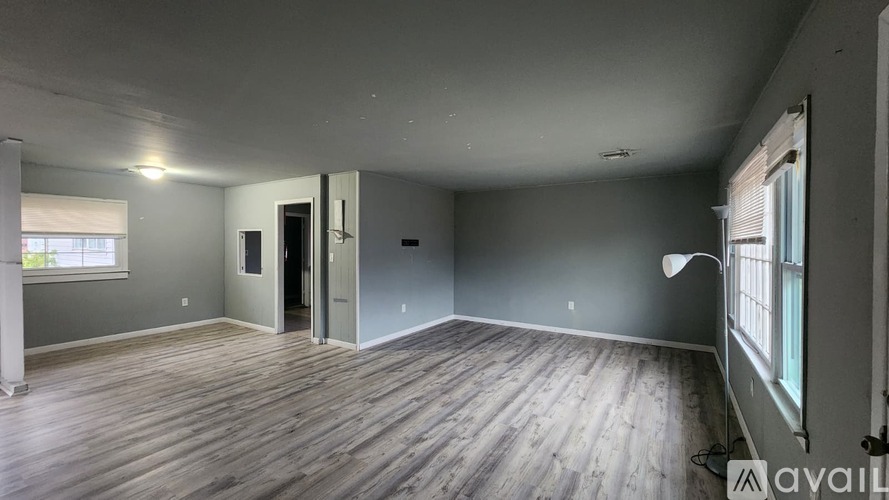 A spacious room with wooden flooring and a large window.