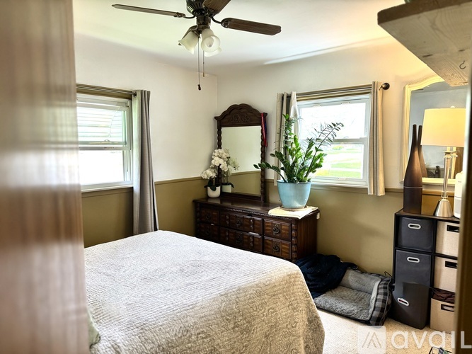 A bedroom with a bed, dresser, and window.