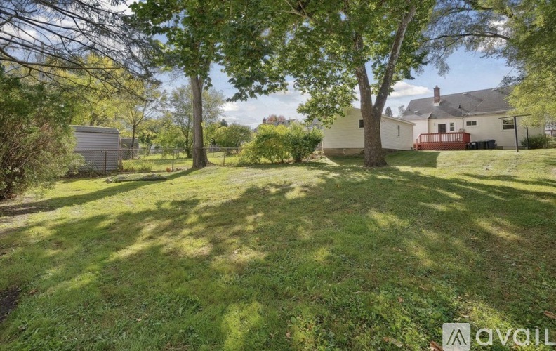 A grassy area with trees and a house in the background.