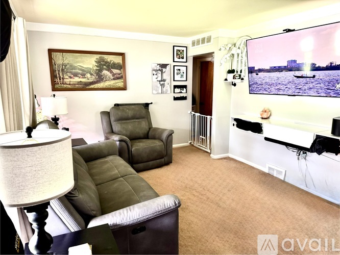 A living room with a couch, chair, lamp, and a painting on the wall.