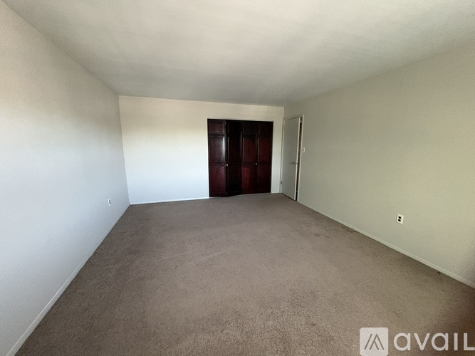 A room with a carpeted floor and a door at the end.