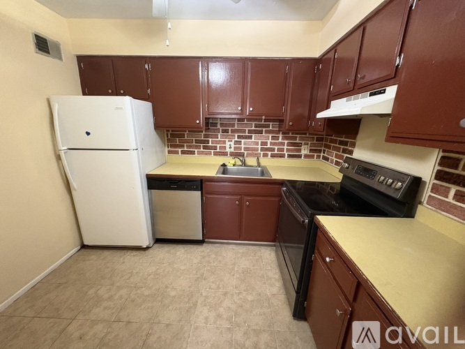 A kitchen with brown cabinets and a white refrigerator.