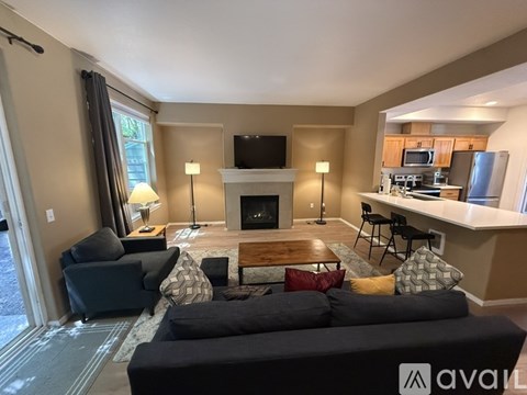 A living room with a black couch and a fireplace.