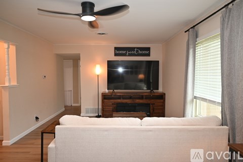 A living room with a white couch and a flat screen TV mounted on the wall.