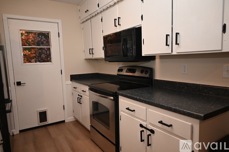 A kitchen with white cabinets and black countertops.